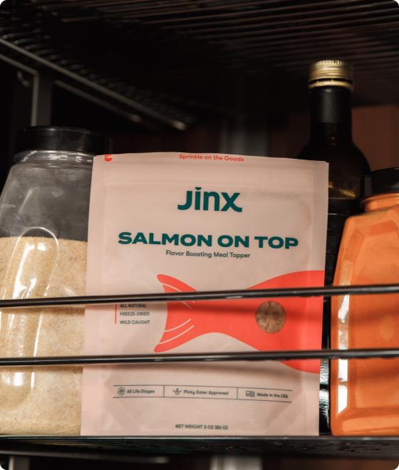 Salmon topper product packaging sitting on a shelf in a pantry amongst other grocery products.