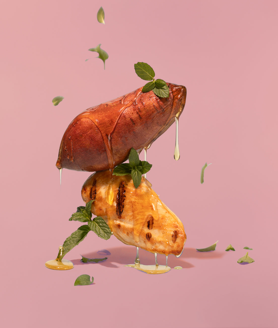 Sweet potatoes dripping in honey with mint, artistically hovering in the air on a pink background