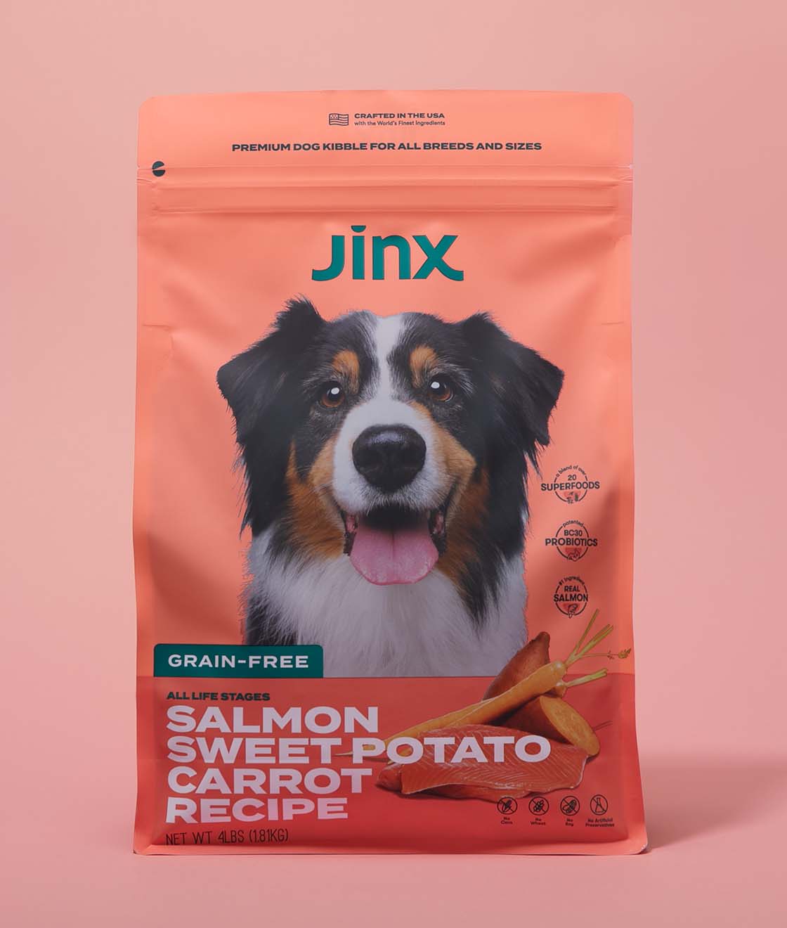 Grain-free salmon essentials Jinx bundle including Salmon, sweet potato & carrot dog kibble product packaging on a pink background.