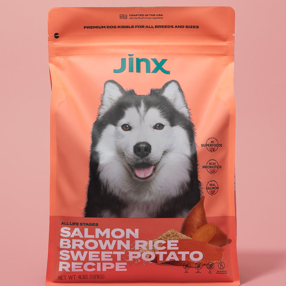 Salmon essentials Jinx bundle including Salmon, brown rice, sweet potato Jinx dog kibble product packaging on a pink background.