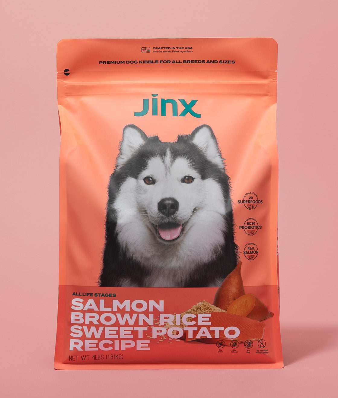 Salmon essentials Jinx bundle including Salmon, brown rice, sweet potato Jinx dog kibble product packaging on a pink background.