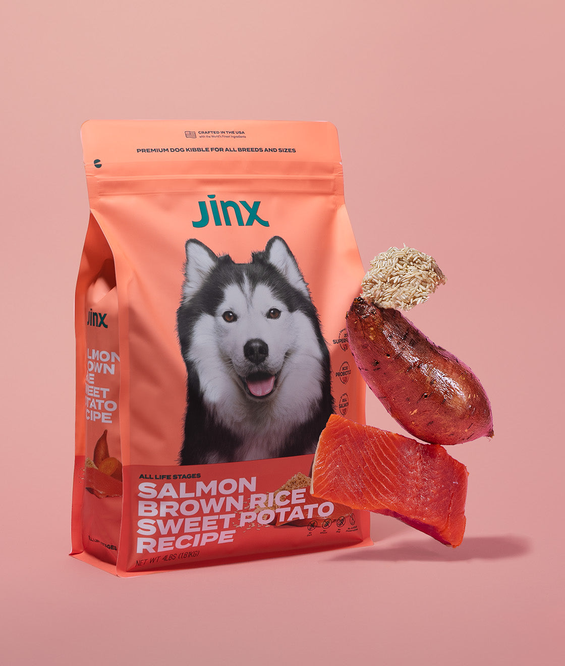 Salmon, brown rice and sweet potato Jinx dog kibble product packaging, with those ingredients hovering in front of it.