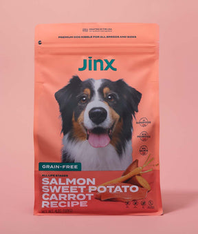 Grain-free salmon essentials Jinx bundle including Salmon, sweet potato & carrot dog kibble product packaging on a pink background.